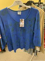 Blue floral patterned long sleeve women's top by CMC on hanger with tag visible
