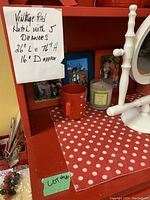 Interior close-up showing note with dimensions, red painted wood, and some items placed on the shelf for scale. Shelf liner with a red background and white polka dots visible.
