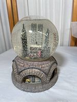 Front angle display of the snow globe showing the Twin Towers, Macy's building, and stone-arched base with yellow taxi inside.