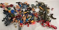 Overview of the assorted collection of toy action figures and vehicle toys spread out on white background, showing various colors and sizes.