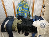 Full view of clothing collection including jeans, jackets, shirts and hoodies displayed on table.