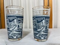 Pair of Niagara Falls glasses with blue and white graphic designs showing Horseshoe Falls and Spanish Aerocar landmarks