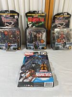 Four boxed collectible action figure sets shown on a white surface.