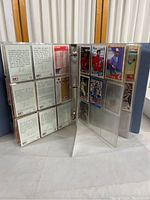 Photo showing inside of binder with sports cards in plastic sleeves, both front and back sides visible. Cards include various baseball and basketball players.