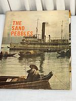 Front cover of The Sand Pebbles movie magazine featuring a sepia photograph of a large steamboat with smaller boats in foreground.