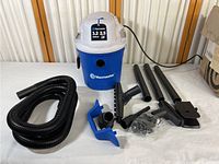 Full set of Vacmaster 3.2 gallon 2.5 HP wet/dry vacuum and accessories including hose, extension wands, brush, nozzle and blower adapter laid out on white surface.
