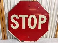 Front view of a vintage stop sign showing the full octagonal shape, red background, white border and white STOP letters. Visible wear and paint chips.