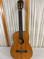 Front view of wooden acoustic guitar showing body, fretboard with no strings, and headstock with tuning pegs.