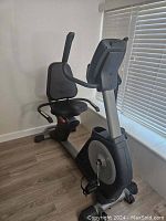 Right side view showing seat, backrest, arm handles, and large flywheel casing.