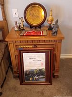 Overview of all Chinese artifacts arranged on wooden table and framed certificate on floor leaning against it.