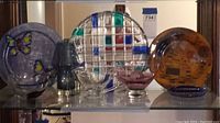Multiple glass serving ware items displayed on shelf including flat dishes, bowls, a gravy boat, and ashtrays
