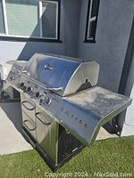 Char-Broil gas grill showing stainless steel body, side shelf, multiple burner controls, and handle on the hood.
