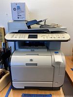 Full front view of HP Color LaserJet CM2320nf printer copier with extra toner box on top