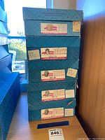 Stack of five blue original boxes labeled Madame Alexander Little Women collection dolls with age recommendation and measurements.
