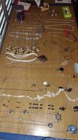 Photo showing multiple necklaces and bracelets laid out on a wooden surface in various styles and materials.