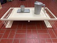 Main white wooden bed tray placed on floor with gray plastic cup, tray, and pitcher on it