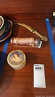 Photo of three items: onyx trinket box, kaleidoscope, and decorative dagger on wooden surface with measuring card.
