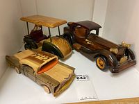 Front view showing the three wooden vehicle models including a vintage classic car, a golf cart, and a car with 'Cuba' engraving.