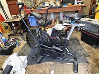 Full side view of Assault Fitness air bike in storage space showing overall condition