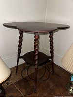 Angle view of the stained clover leaf table showing twisted legs and lower shelf.