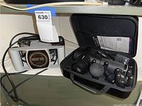 Fusion massage gun in charging stand next to open carrying case with attachments and charger.