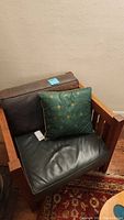 Full view of mission-style wooden armchair with leather cushions and decorative pillow