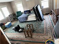 Wide view of the large rug spread out on the floor with mattress and other items on top to show scale and condition