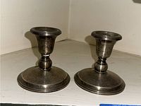 Front angled view showing pair of silver weighted candle holders with round base