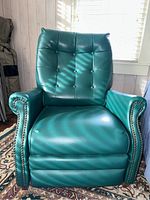 Front view of the green vintage recliner chair showing tufted backrest and nailhead trim on arms.