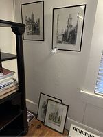 Four framed architectural sketches by Oscar Schenk displayed on and against a wall in a corner.