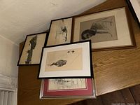 Group of five framed black and white artworks on tabletop stacked together