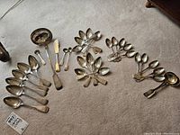 Multiple clusters of spoons spread on carpet showing overall lot size and grouping