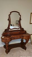 Full front view of antique mahogany vanity with large curved mirror and three drawers on top and one drawer below