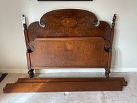 Full view of wooden double bed frame showing headboard, footboard, and side rails on carpeted floor.
