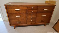 Front view showing six drawers, metal pulls, tapered legs