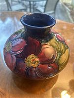 Front view of spherical vase with red and green Clematis pattern.