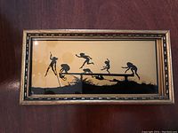Front view of the framed silhouette painting depicting six playful monkeys in black on beige background.