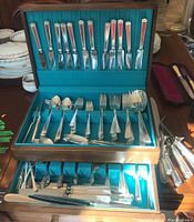 Full view of the open wooden case showing the organized silver-plated flatware including knives, forks, spoons, and serving utensils with teal lining.