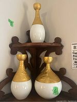 Three porcelain candleholders displayed on a wooden corner shelf