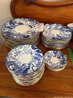 Several stacks of blue and white plates and fruit nappies displayed on wooden surface