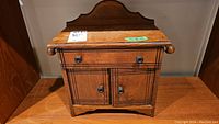 Front view of the wooden shoeshine box showing drawer, cabinet doors, and carved details