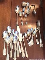 Full assortment laid out on table showing large spoons, small spoons, tongs, ladles and spreader.