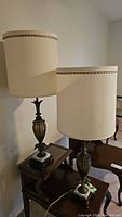 Pair of vintage lamps on small tables against wall, showing full height and shades