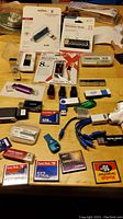 Photo displaying multiple USB flash drives, memory cards, charger cables, and card readers laid out on a table