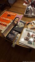 Full view of the lot displayed including Judy Garland concert poster, boxed CD and cassette sets, TV Guide magazine, Legends of the Silent Screen stamp book, and a glimpse of an Oz-Time watch.