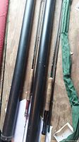 Two fly fishing rods side by side with their carry tubes, showcasing cork handles and black rod bodies.