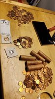 Full lot arranged on a wooden table including several piles of pennies, rolls of pennies wrapped in brown paper, and individual coins in protective plastic holders.