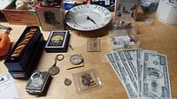 View of multiple small collectibles on a table including wooden kaleidoscope, playing cards, coins, clock, and pins