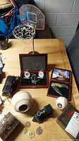 Overall shot showing metal basketball backboard with net, two animal figure pocket watches in box, softball clock, plastic toy train, coins, medallions, metal and plastic collectible boxes, and old camera.