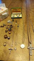 Overview of all items arranged on table showing rings, necklaces, cufflink set, brooch, tie clip, and pendants
